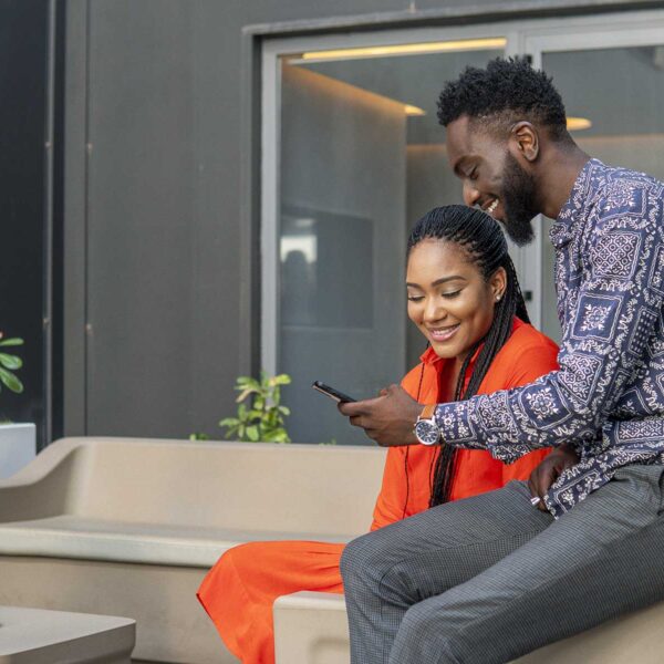 a man and woman sit on a couch looking at a cell phone