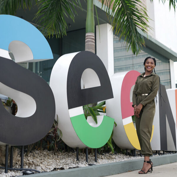 a woman stands in front of a sign that says seen