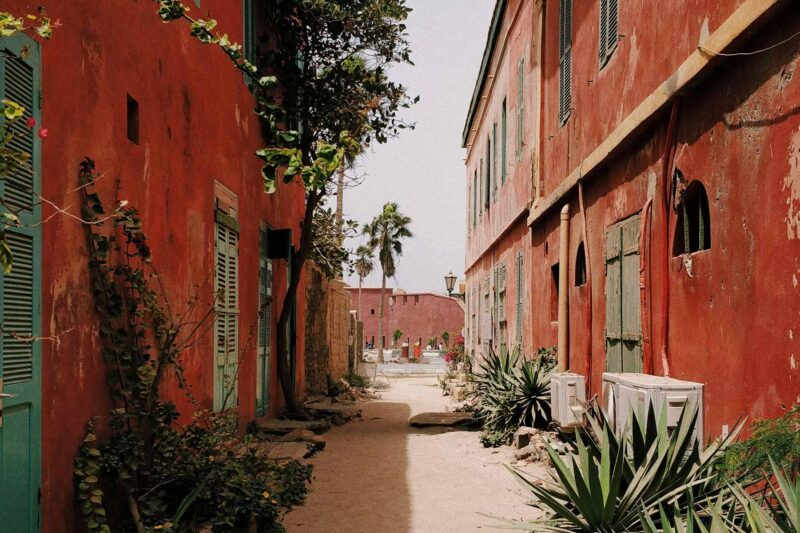 une rue étroite avec des bâtiments rouges et des fenêtres vertes