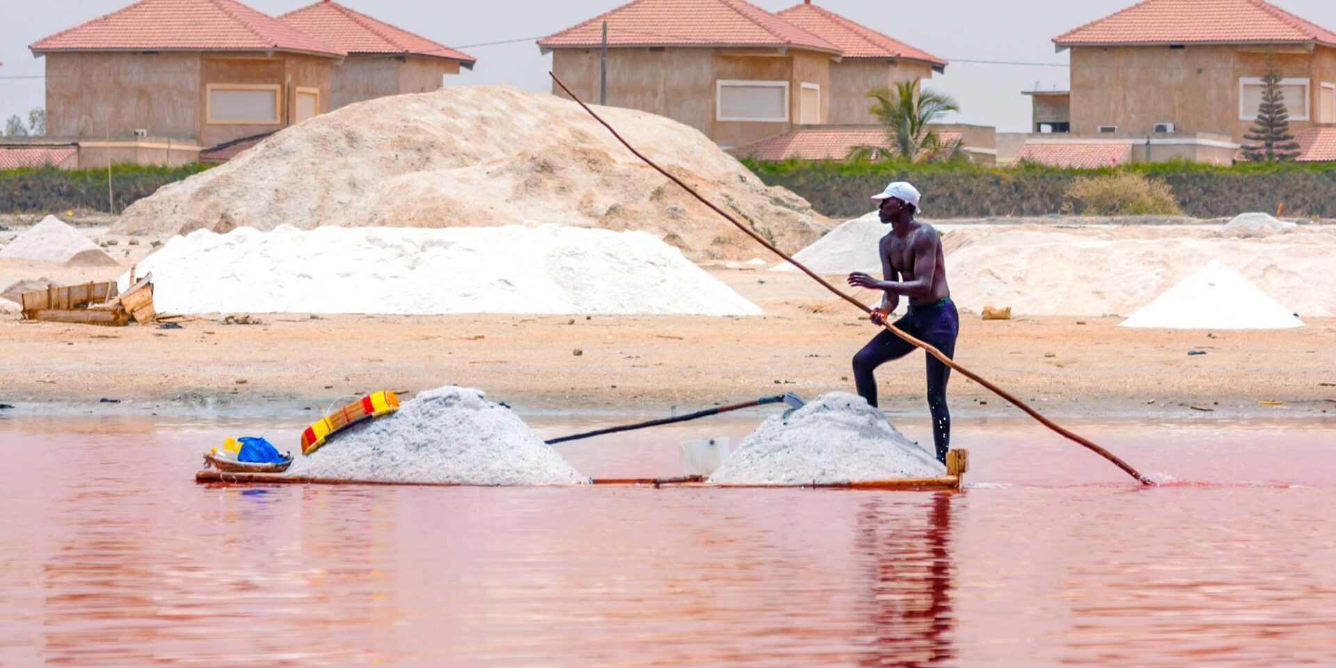 a man in a white hat is rowing a boat in the water