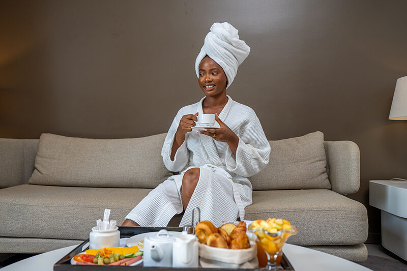 a woman in a bathrobe sits on a couch holding a cup of coffee