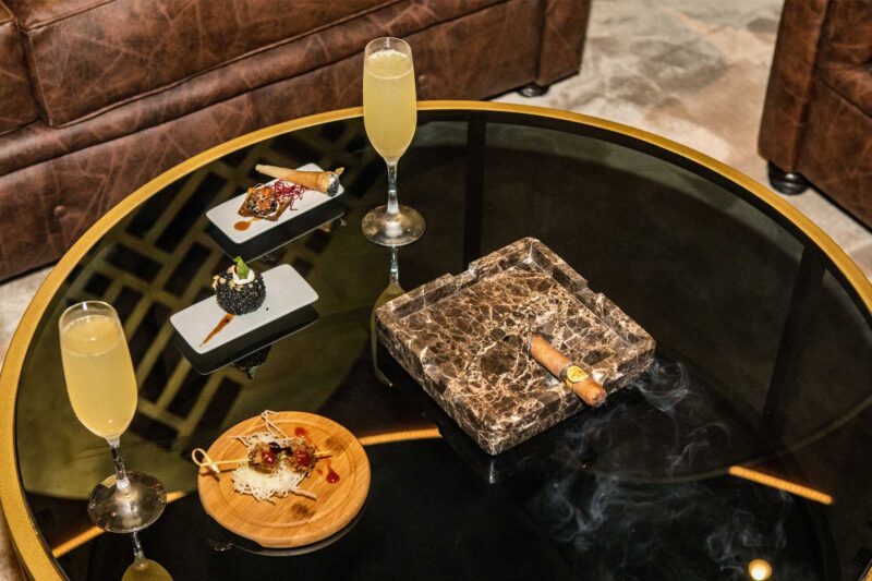 a table with a cigar and two glasses of champagne