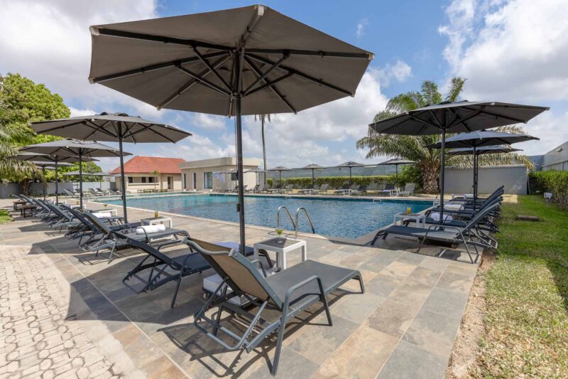 a swimming pool with chairs and umbrellas around it