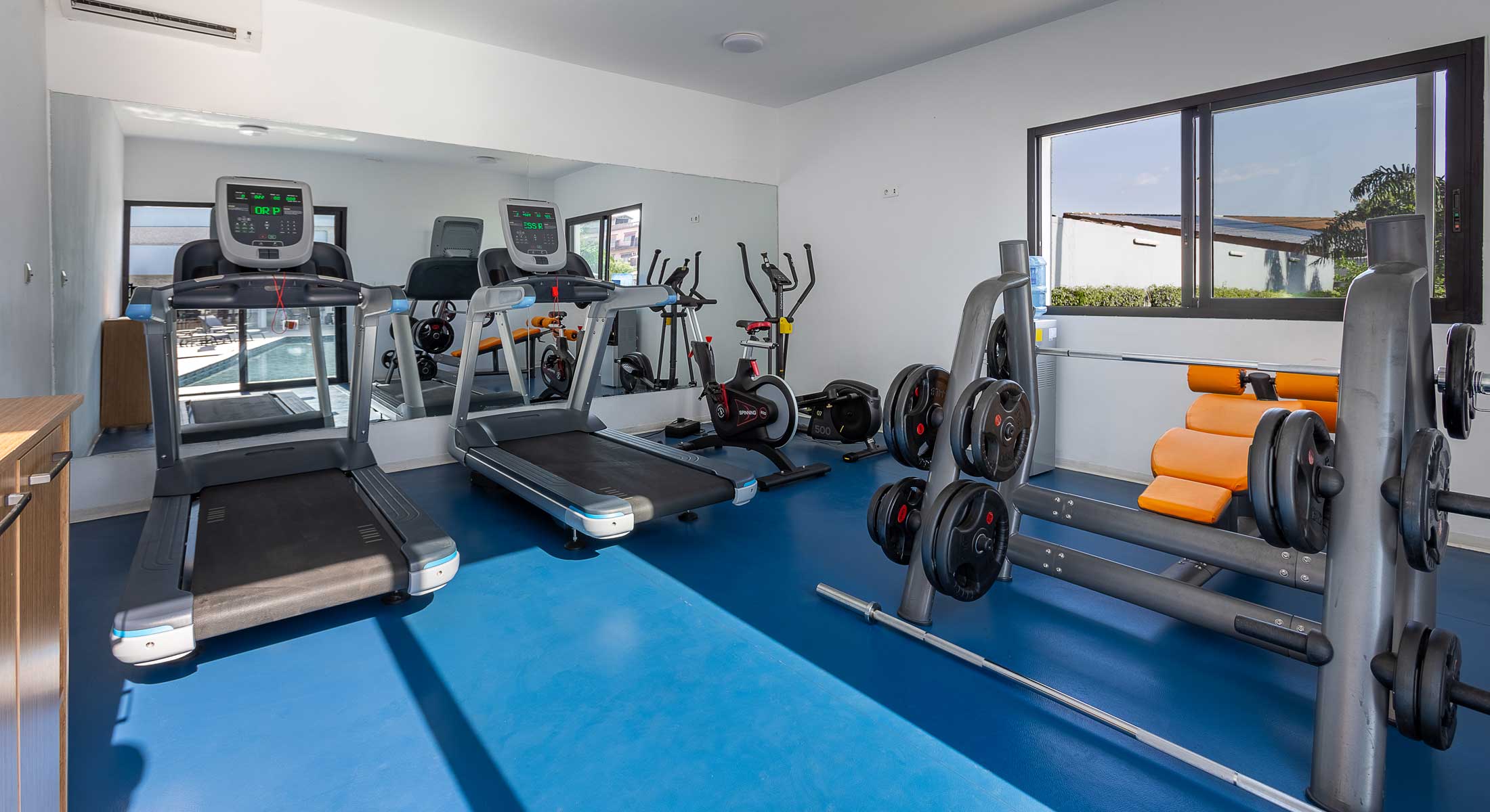 une salle de sport avec un tapis roulant et des haltères