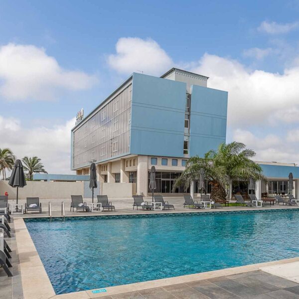 a large swimming pool with chairs and umbrellas in front of a hotel