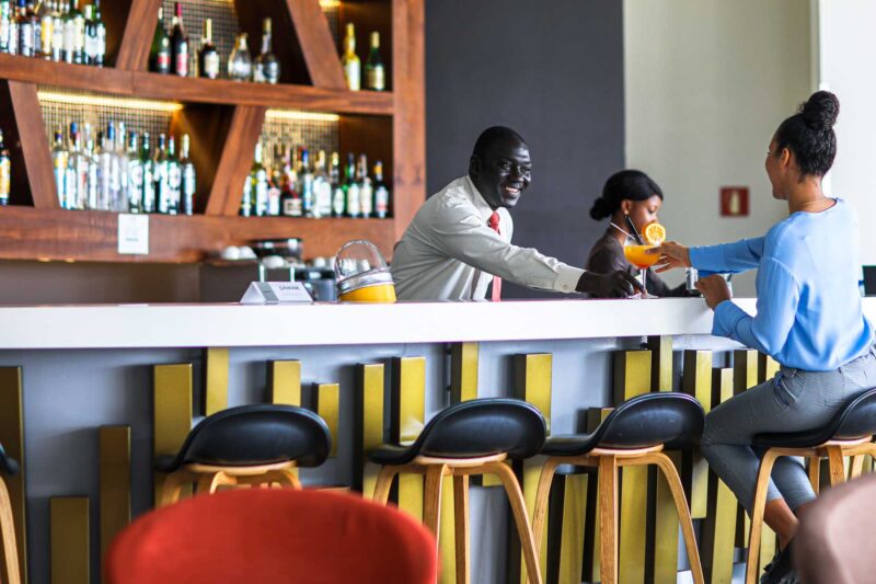 a woman sits at a bar while a man serves her a drink