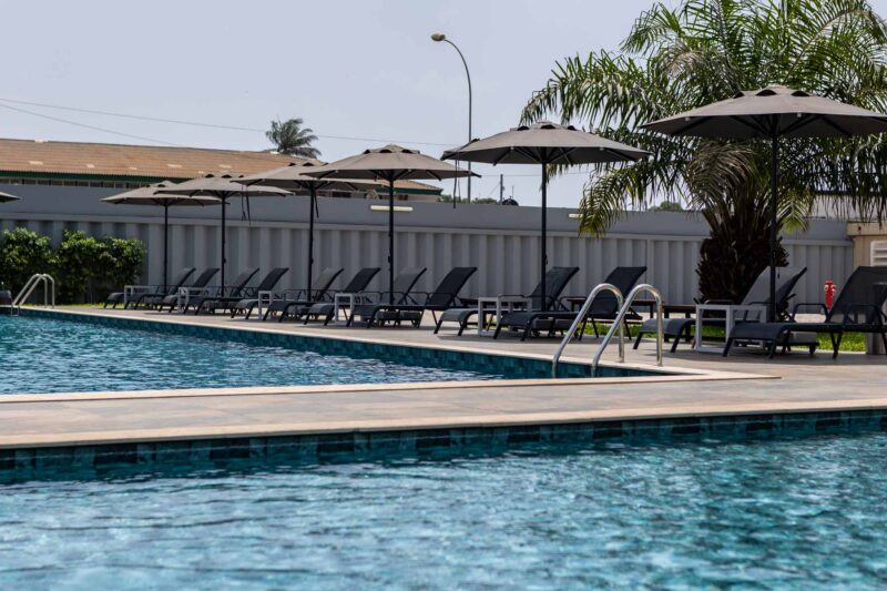 a swimming pool with chairs and umbrellas around it