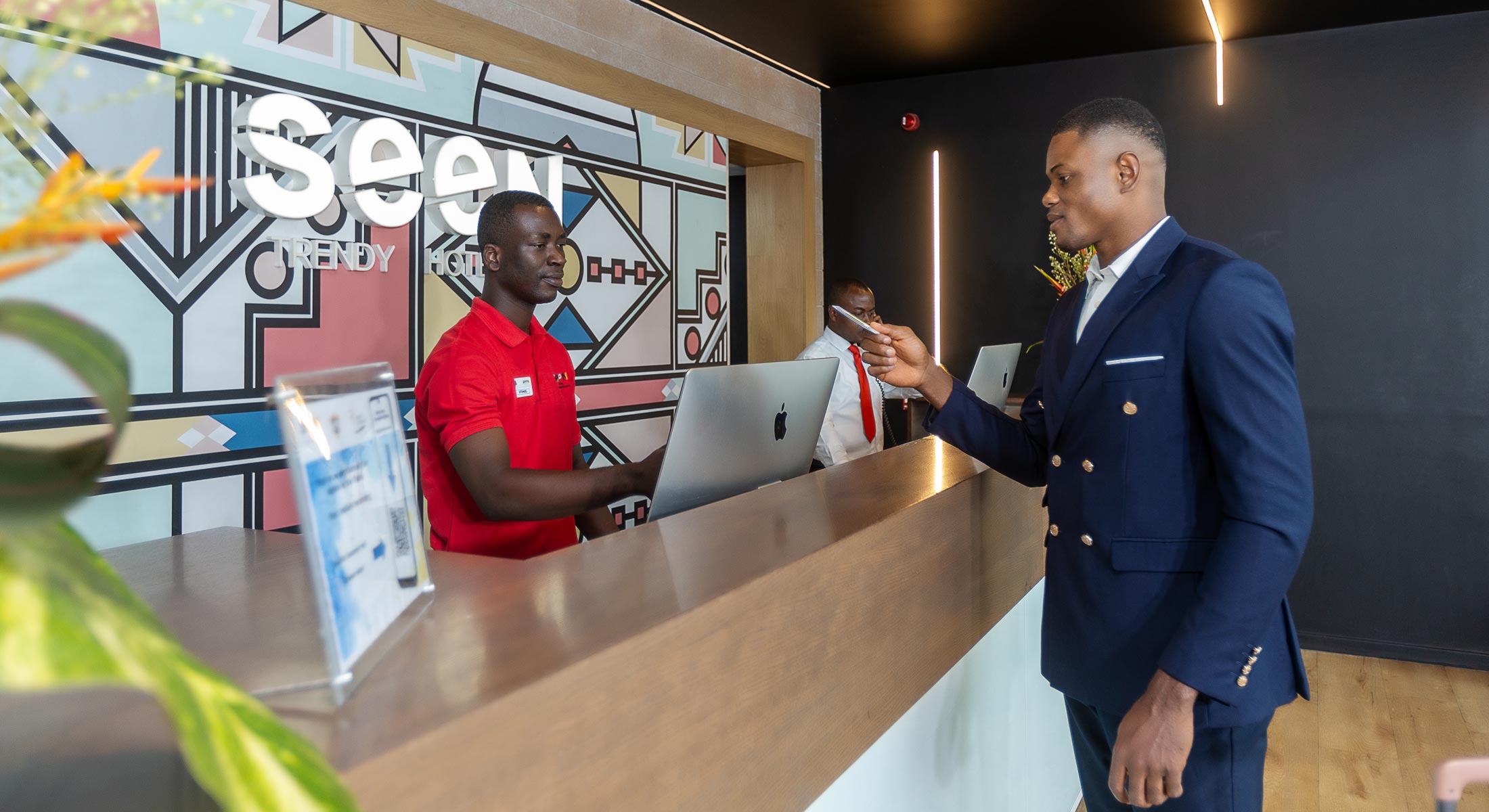 un homme en costume se tient à un comptoir avec un homme en chemise rouge