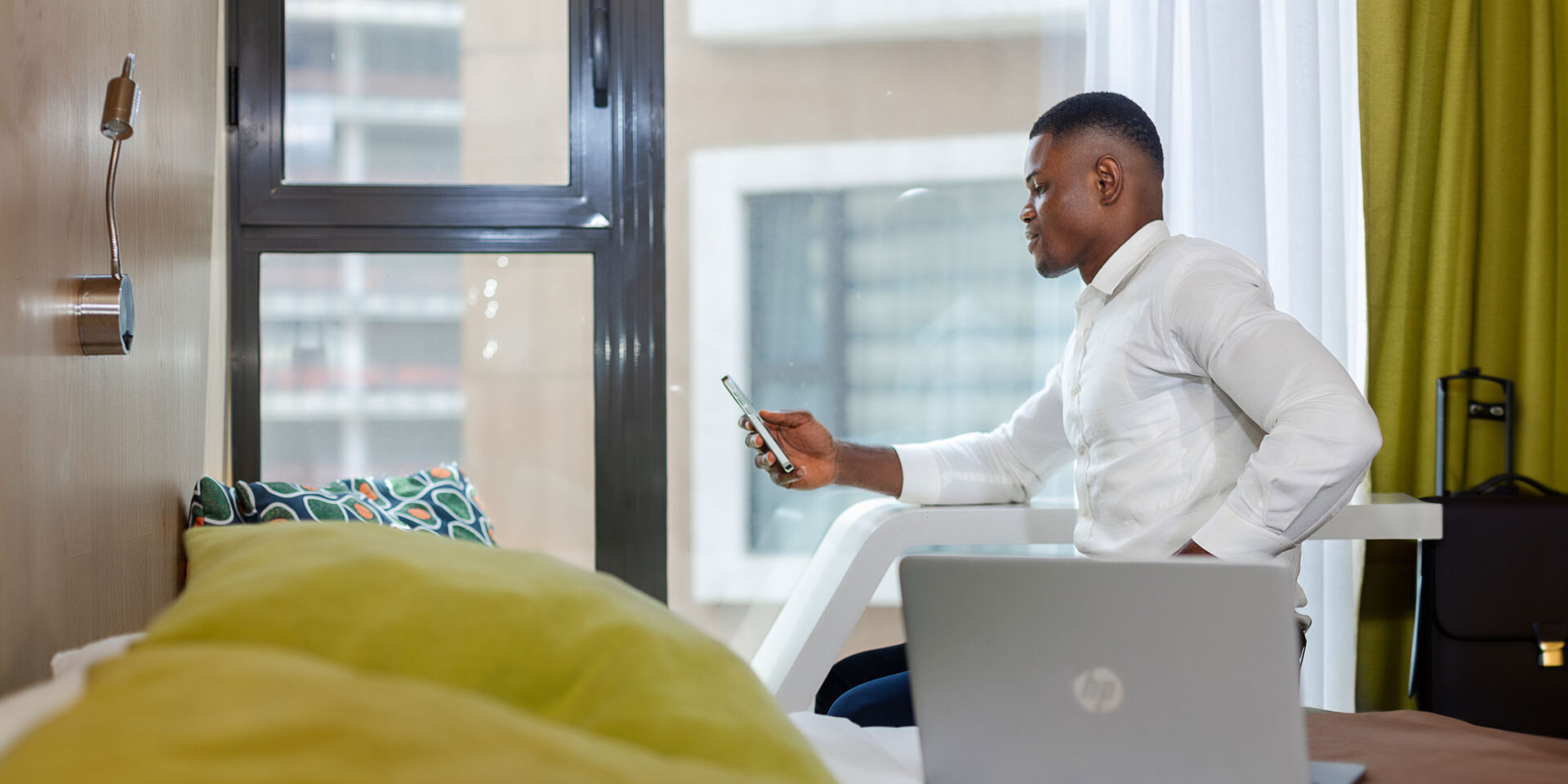 a man sitting on a bed with an HP laptop