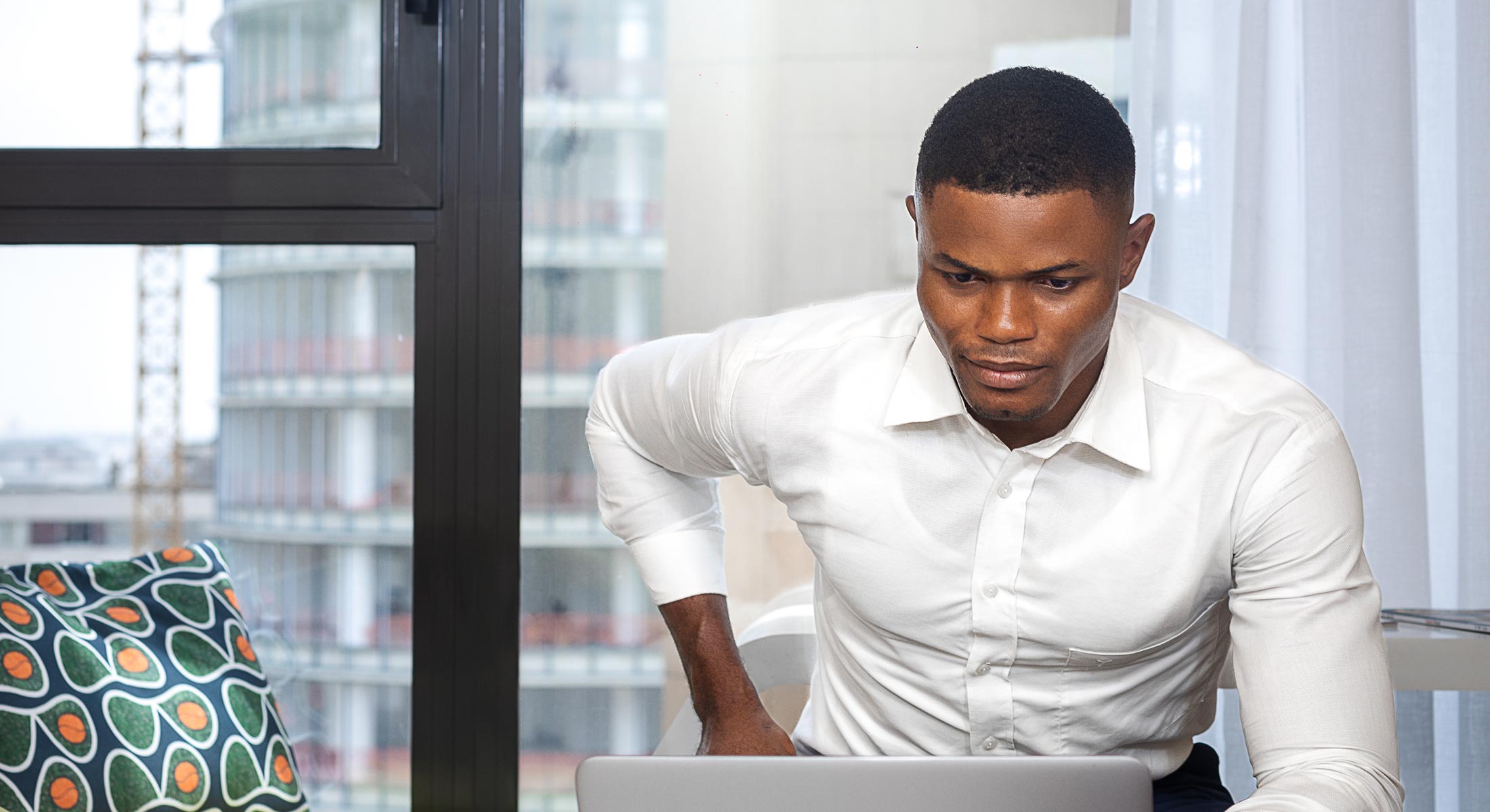 un homme en chemise blanche travaille sur un ordinateur portable