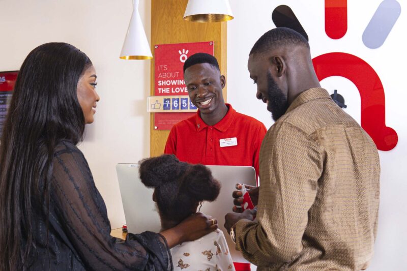 un homme, une femme et une enfant se tiennent devant la réception d'un hôtel YAAS