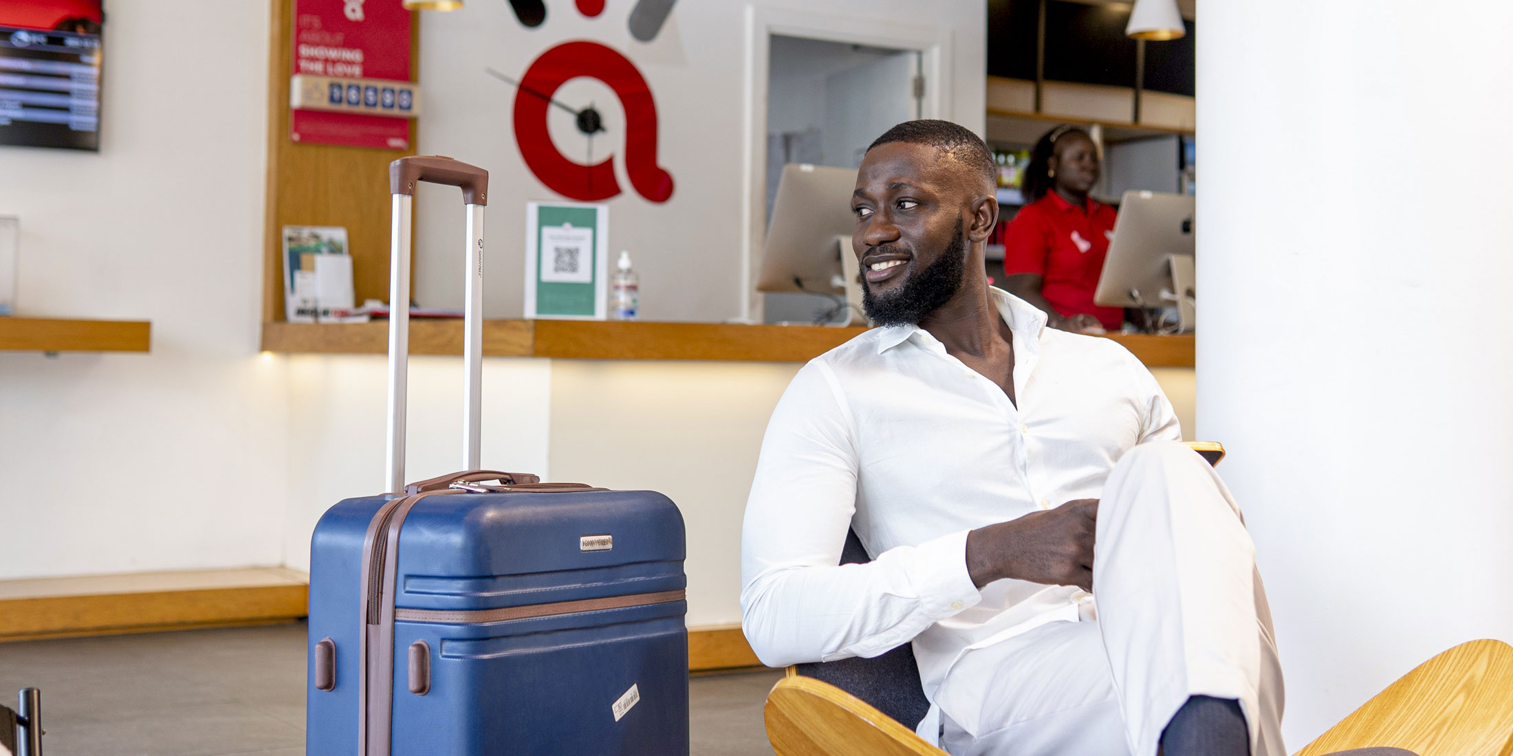 un homme assis à côté d' une valise bleue