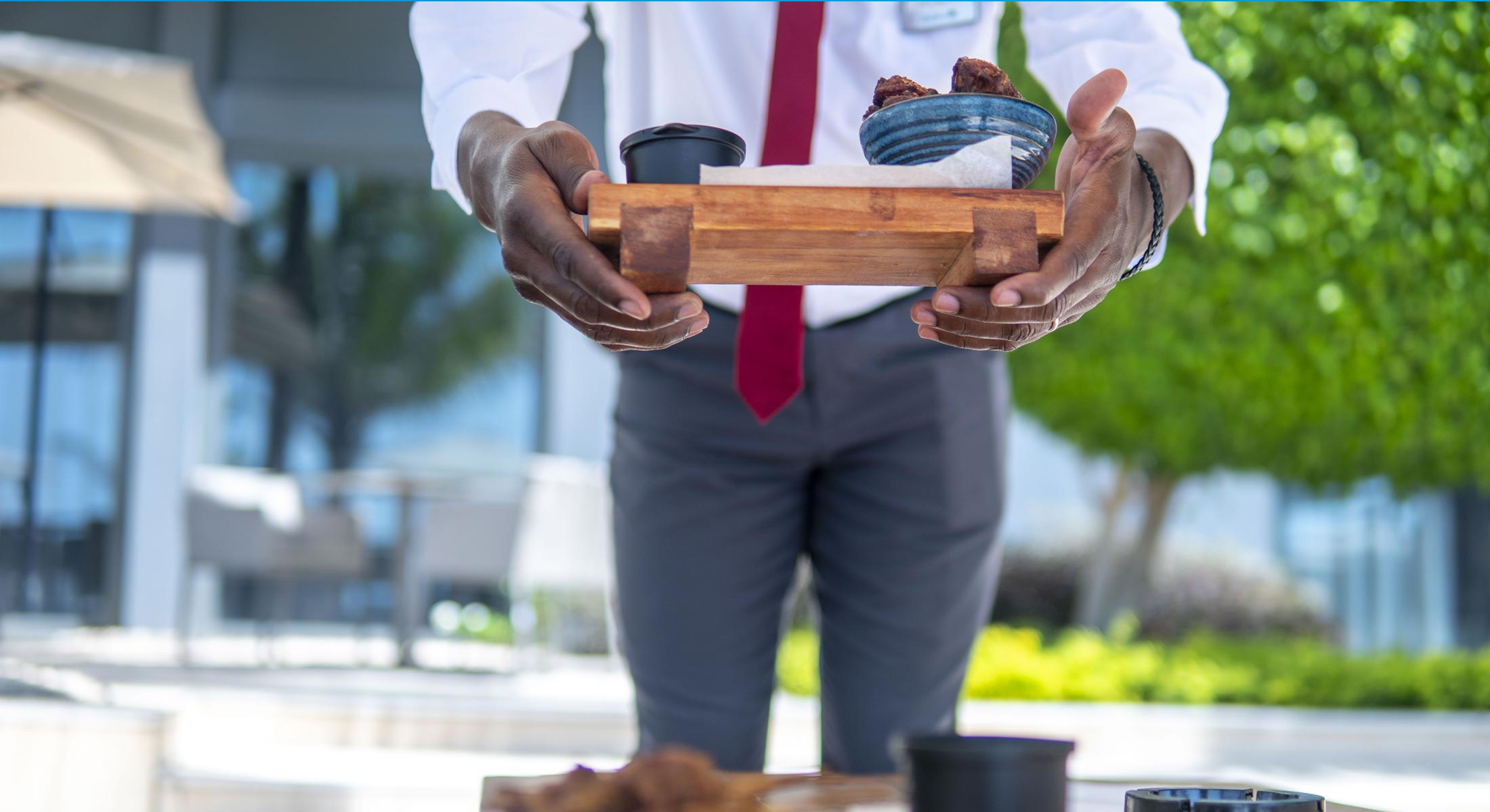 a man in a white shirt and red tie is holding a tray of food