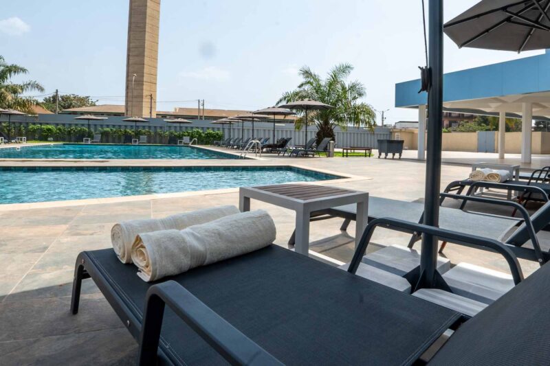 a swimming pool with chairs and umbrellas around it