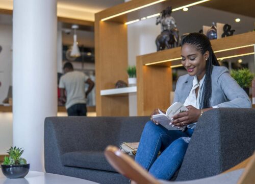 une femme est assise sur un canapé en train de lire un livre