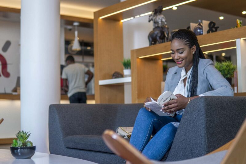 une femme est assise sur un canapé en train de lire un livre