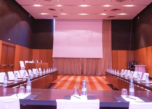 a conference room with tables and chairs and a projector screen