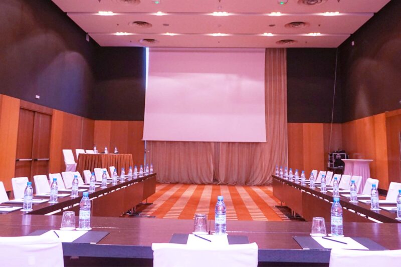 a conference room with tables and chairs and a projector screen