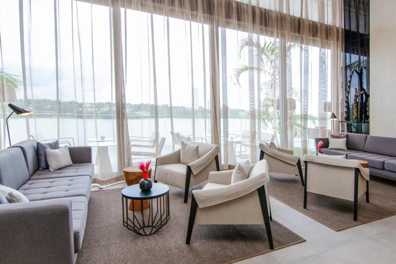 a living room with a couch and chairs with a view of a lake