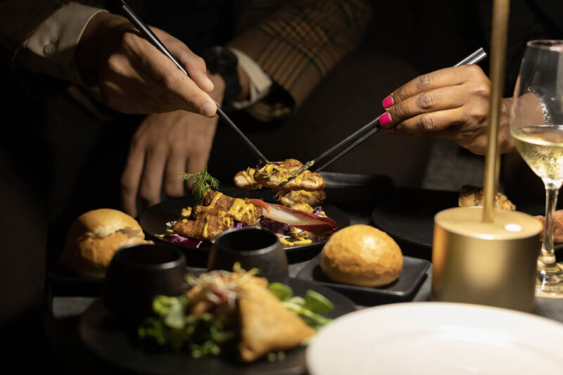 a woman with pink nail polish is eating food with chopsticks