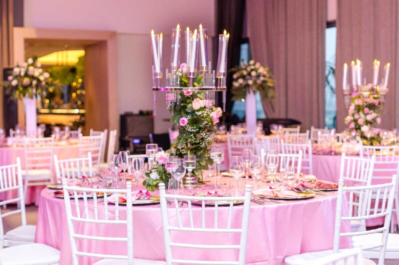 a table with a pink table cloth and white chairs