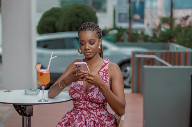 une femme est assise à une table avec un téléphone portable