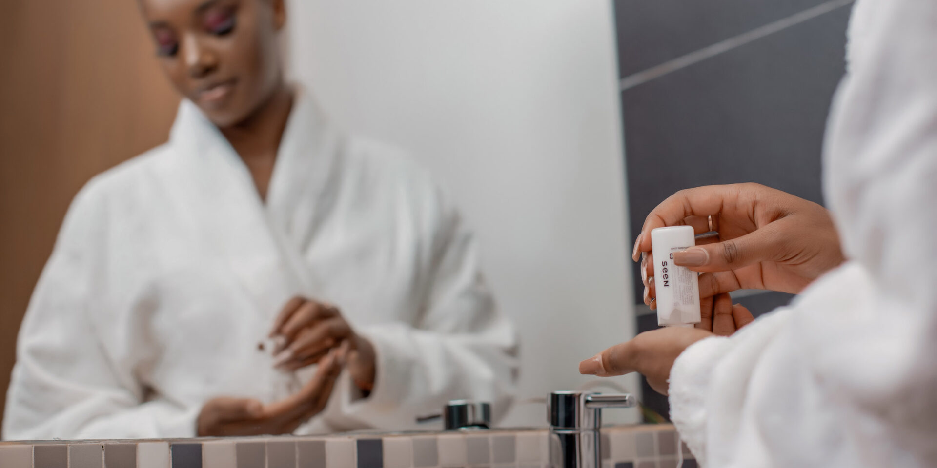 une femme se tient devant un miroir tenant une bouteille de lotion