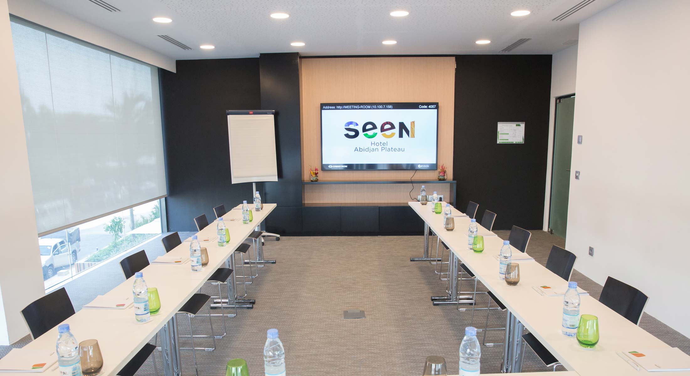 une salle de conférence avec des tables et des chaises et un écran avec le logo