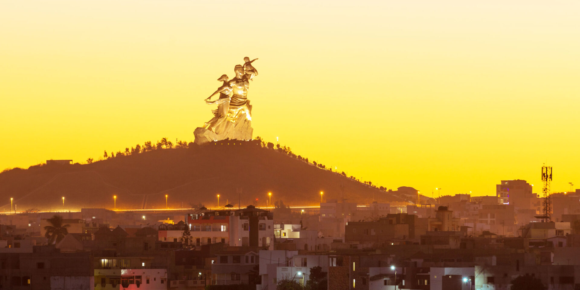 une ville la nuit avec une grande statue au sommet d'une colline