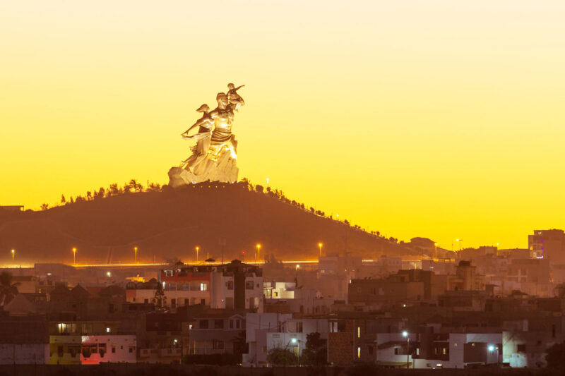 une ville la nuit avec une grande statue au sommet d'une colline