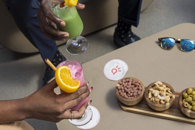 a person holding a drink next to a bowl of nuts