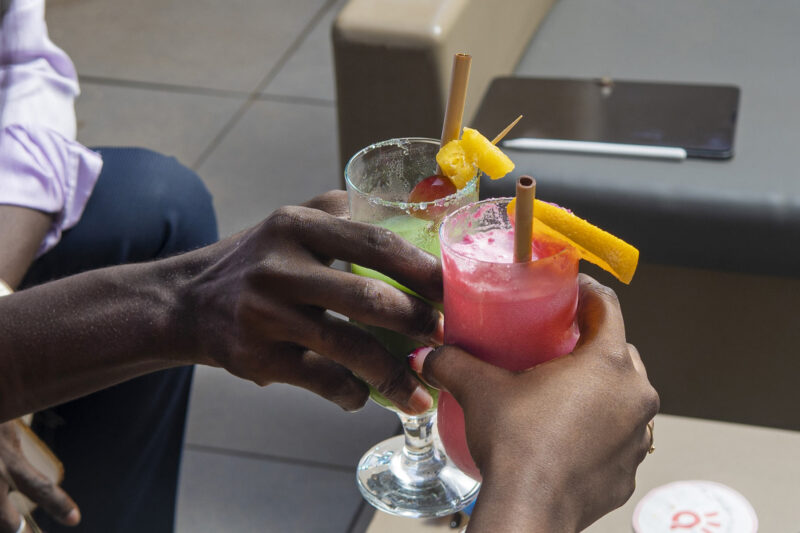 a couple of people toasting with drinks with straws in them