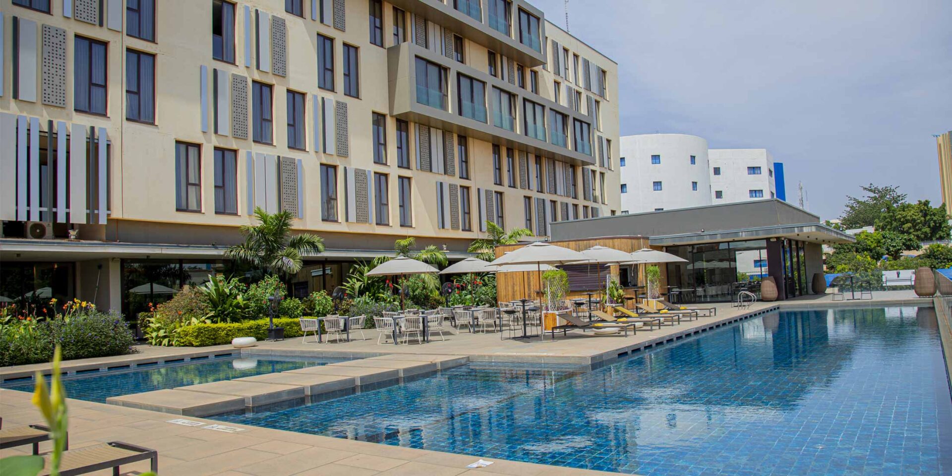 une grande piscine entourée de chaises et d' parasols à côté d' un grand bâtiment