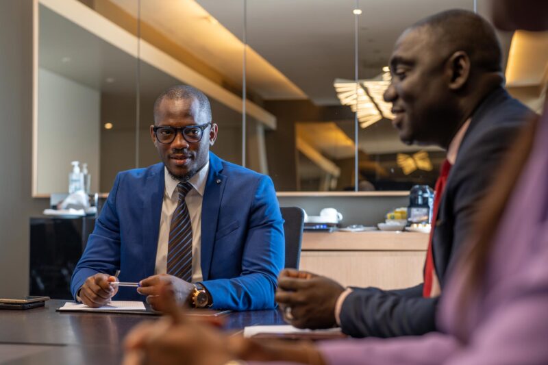 un homme en costume bleu est assis à une table avec d'autres personnes