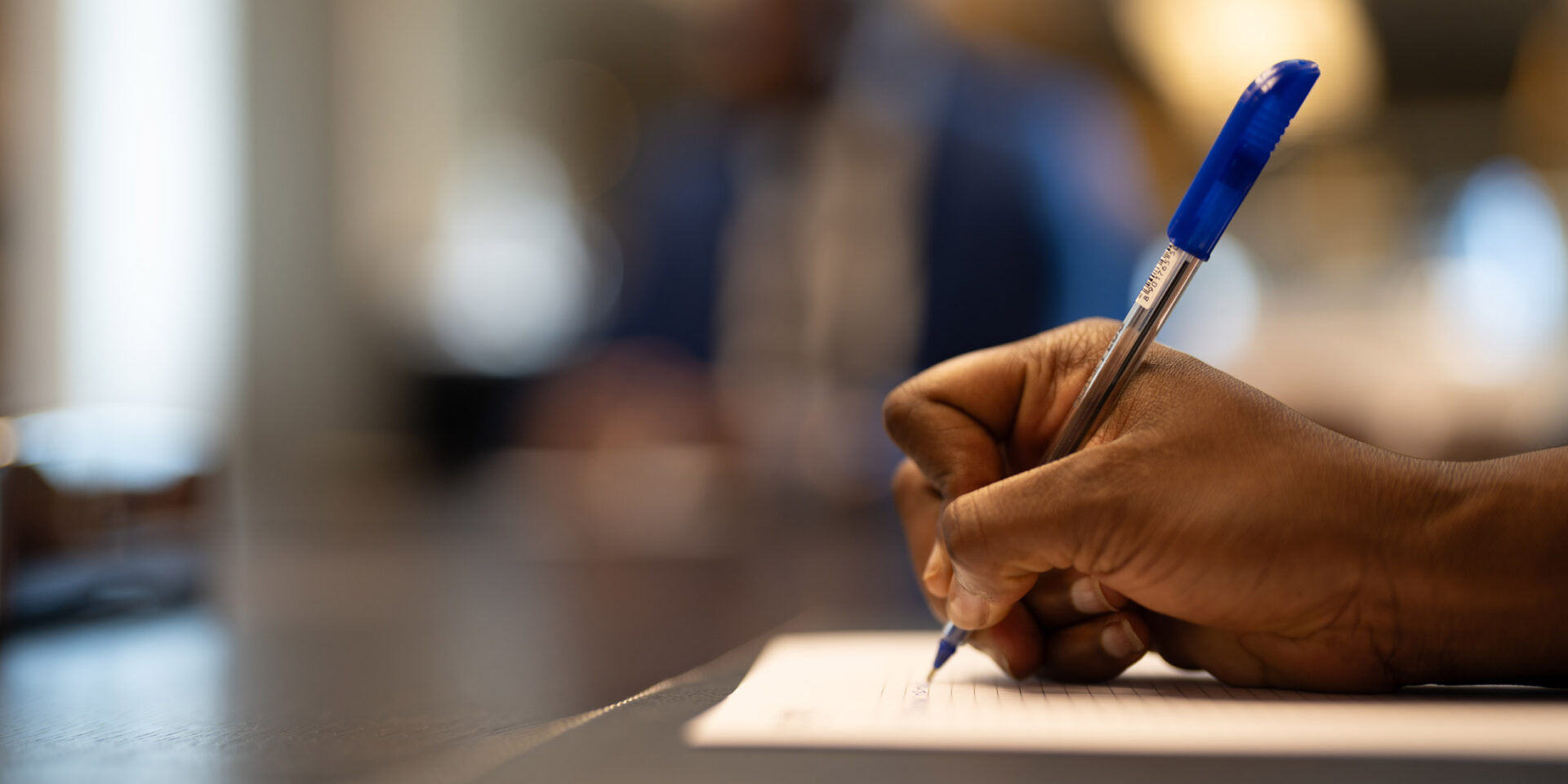 une personne écrit avec un stylo bleu sur un morceau de papier