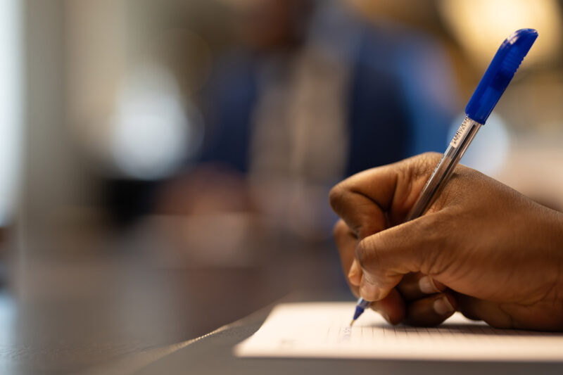 une personne écrit avec un stylo bleu sur un morceau de papier