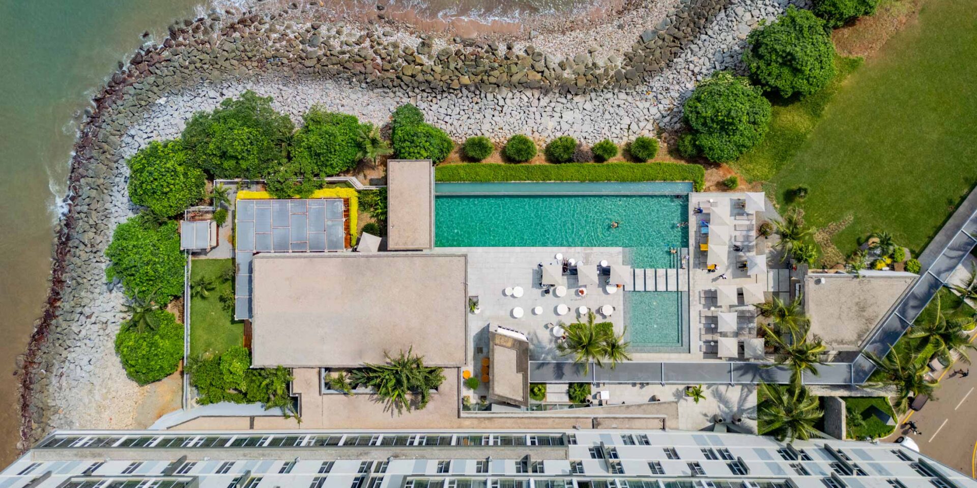 une vue aérienne d' un grand bâtiment avec une piscine à côté de l' océan