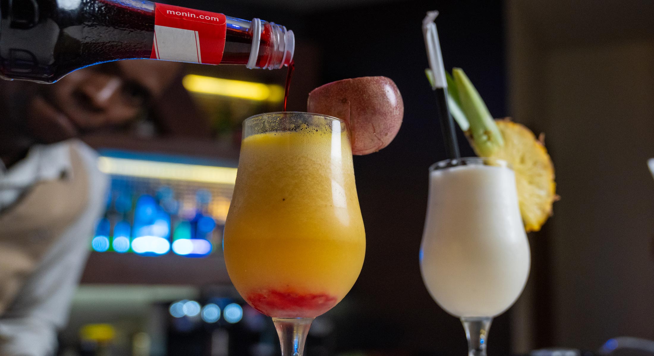 un barman verse un cocktail dans un verre à côté d' une bouteille de 