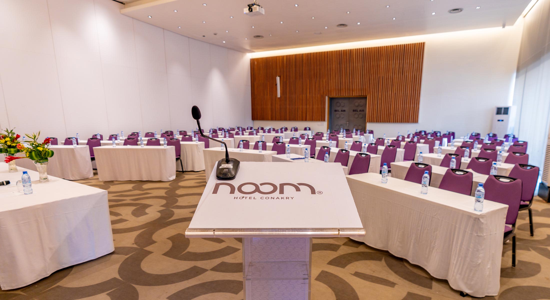 une salle de conférence avec des tables et des chaises et un pupitre avec le logo noom