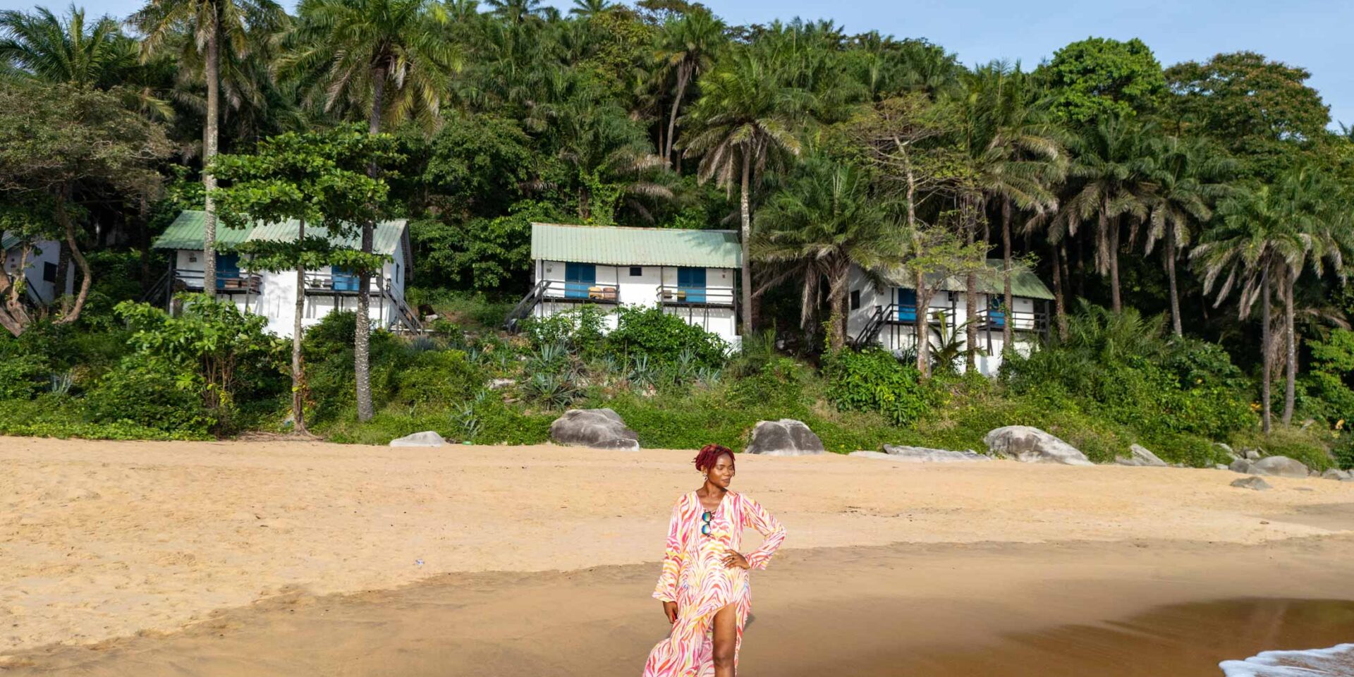 a woman in a long dress is standing on a beach