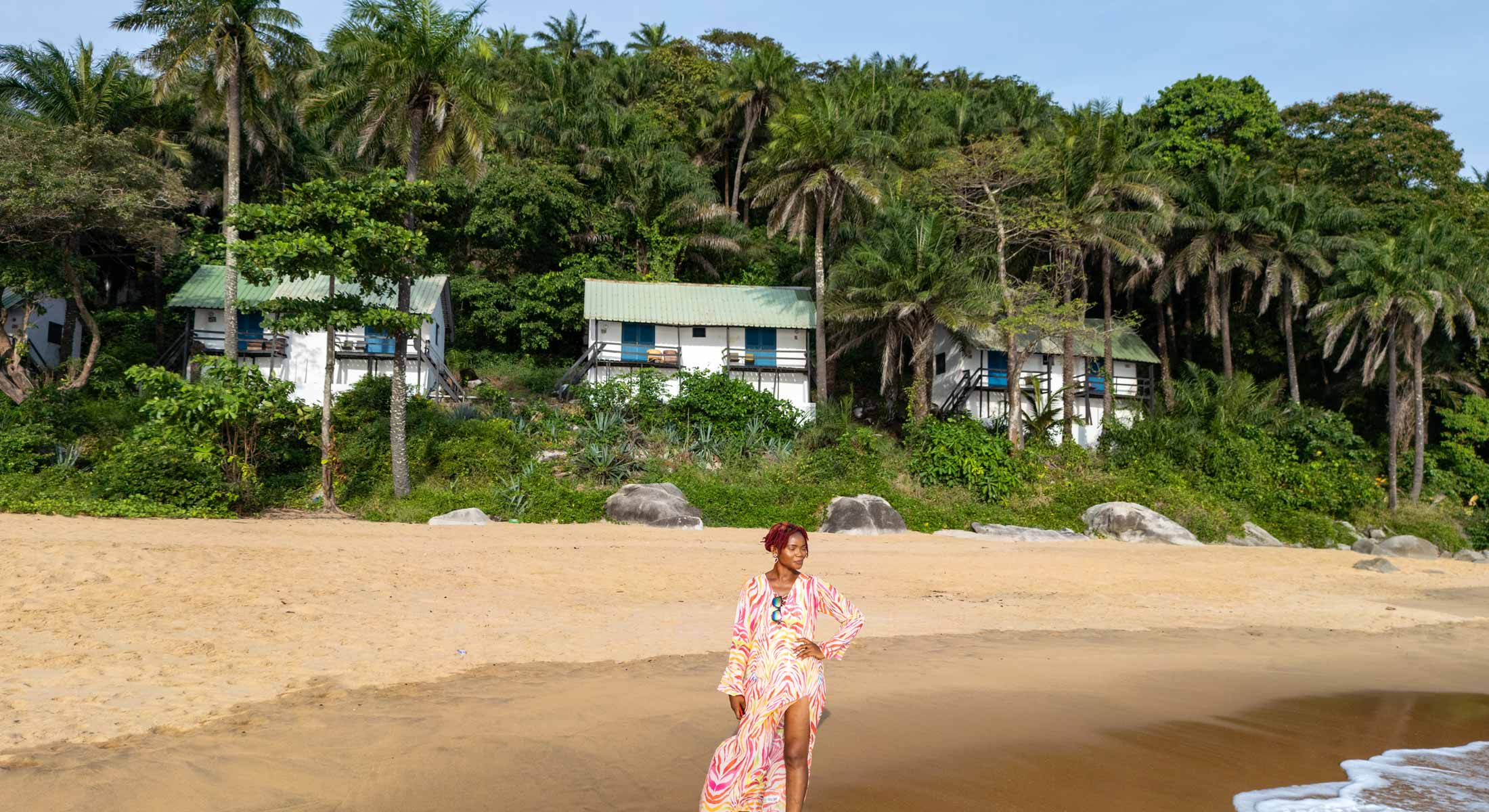 une femme debout sur une plage avec des maisons en arrière-plan