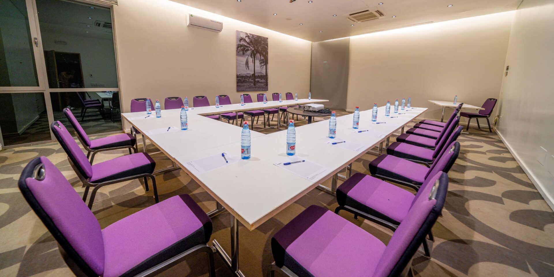 une salle de conférence avec une table blanche et des chaises violettes