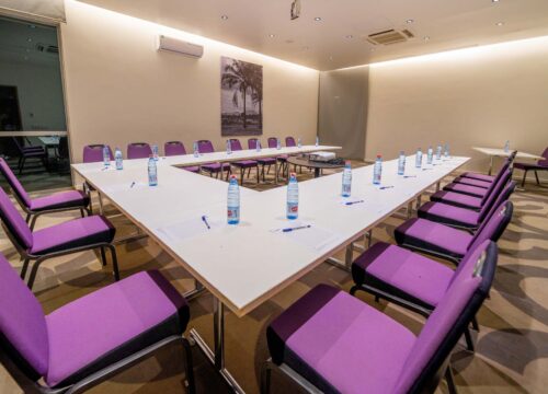 une salle de conférence avec une table blanche et des chaises violettes