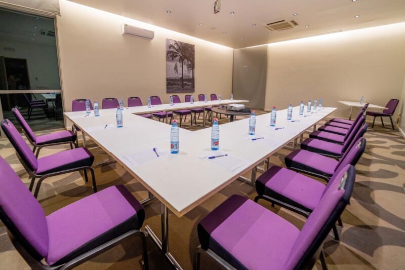 une salle de conférence avec une table blanche et des chaises violettes