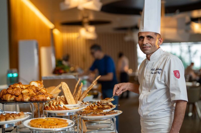 a chef wearing a chef 's hat and a chef 's jacket with the letter c on it