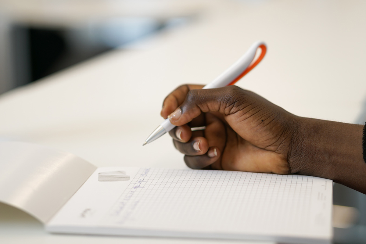 a person is writing on a piece of paper with a pen