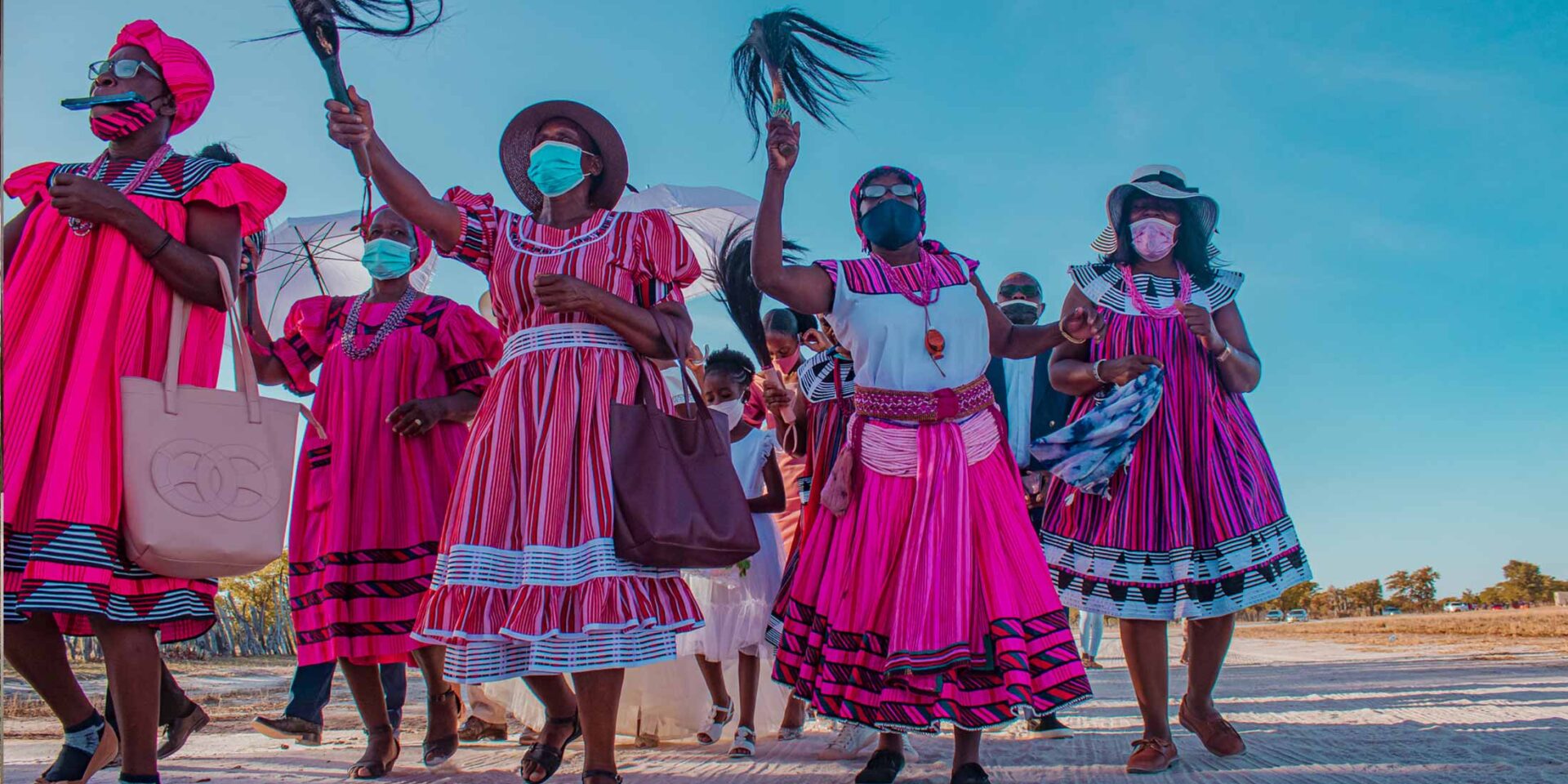 a group of women wearing pink dresses and face masks