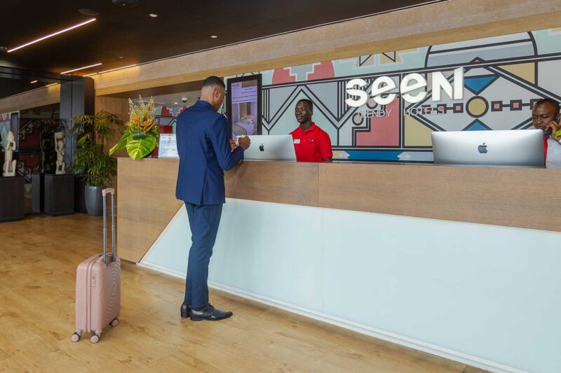 un homme avec une valise se tient à la réception d' un hôtel