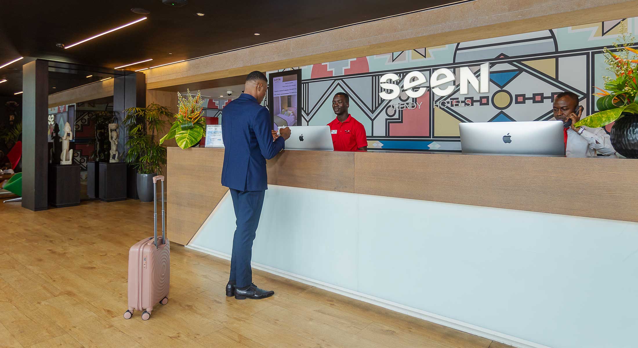 un homme avec une valise se tient à la réception d' un hôtel