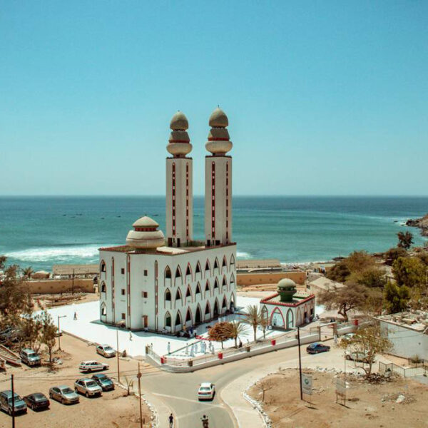 a large white building with two minaret shaped towers sits next to a body of water